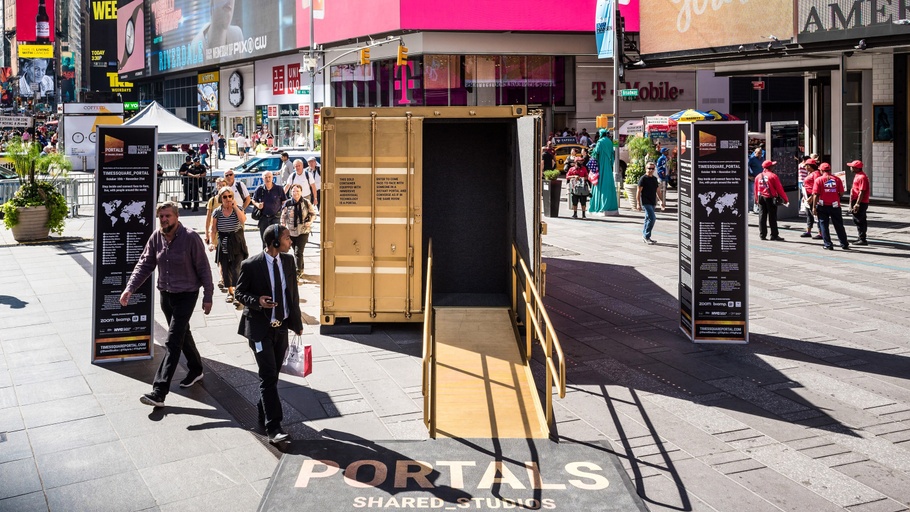 A gold shipping-container Portal open on a Times Square sidewalk